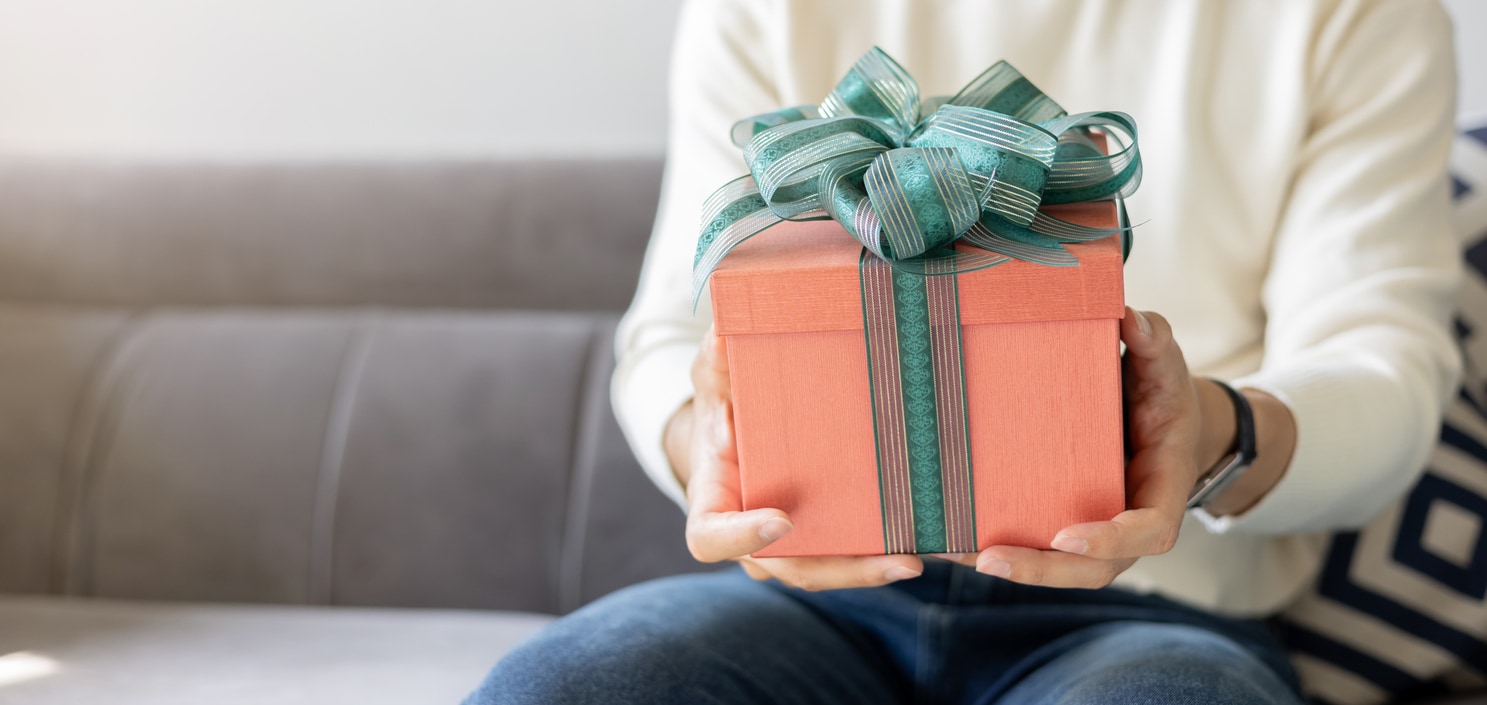 een man op de bank die een kado krijgt